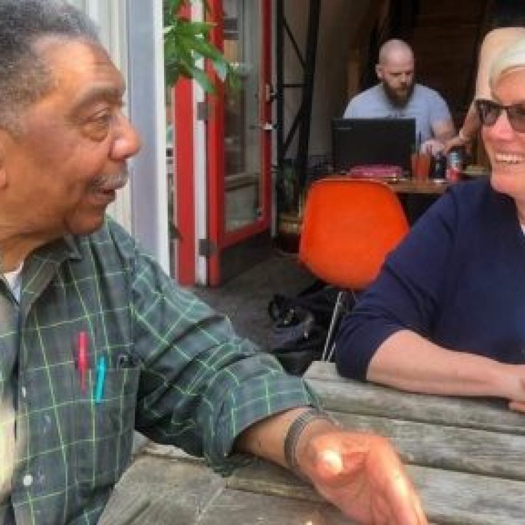 Harvey Rice and Loulie Brown having a conversation sitting down at a table